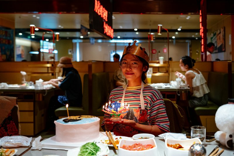 Girl smiling at the camera holding birthday cake and presents